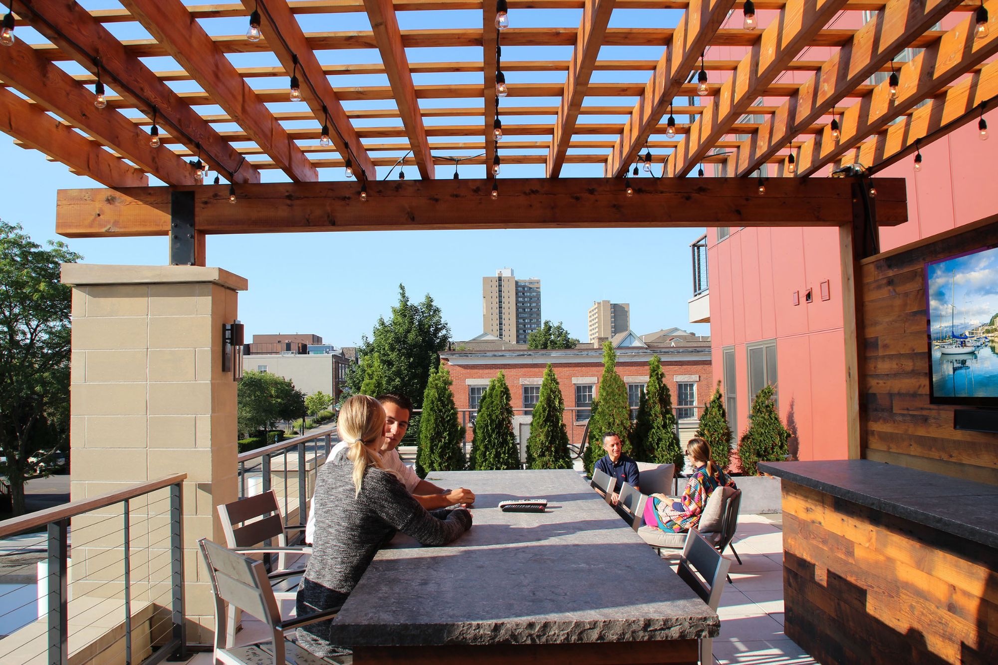 Residents under the rooftop pergola with the skyline behind